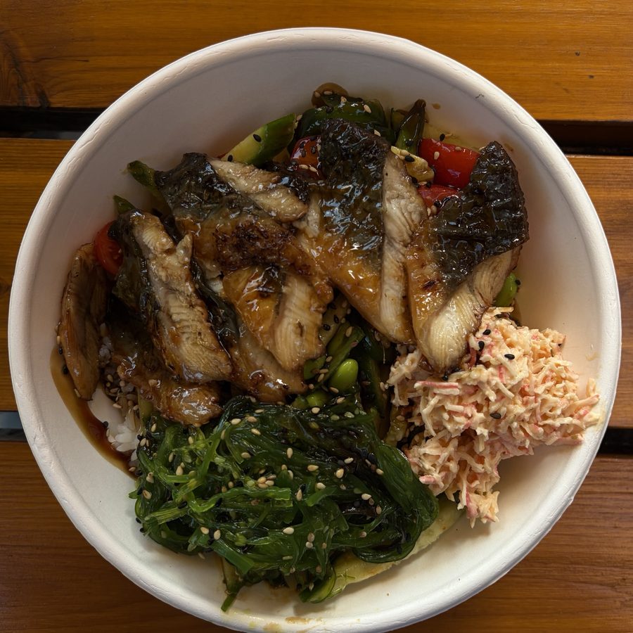 A rice bowl with glazed fish, seaweed salad and vegetables