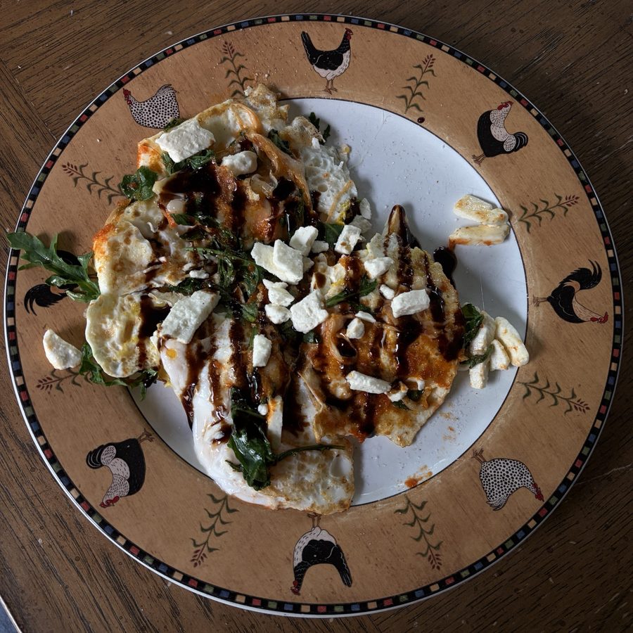 Fried eggs with arugula and feta on a painted plate