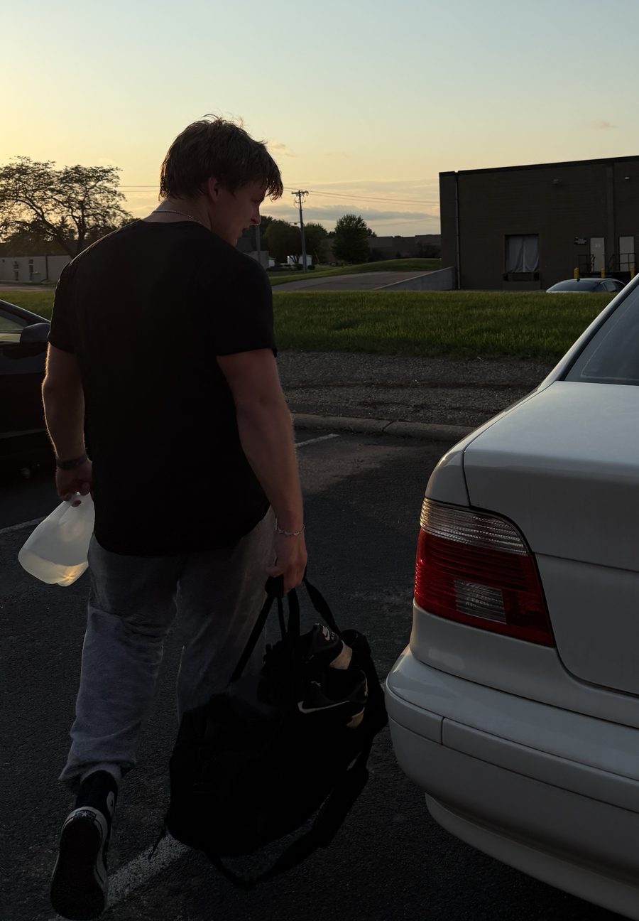Stepan walking to his car at sunset with a gym bag and water jug